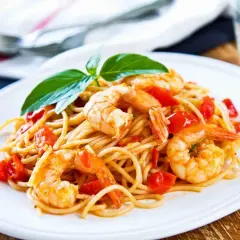 Spaghetti con gamberetti succulenti e pomodorini freschi, guarniti con basilico. Un piatto invitante che profuma di mare.