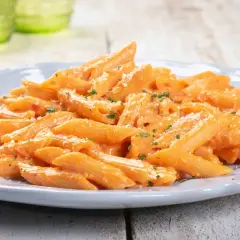 Penne cremose con salsa rosa, un'idea per primi piatti sfiziosi. Spolverata di parmigiano e prezzemolo fresco.