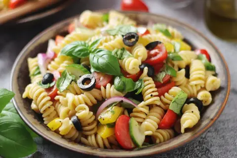 Pasta fredda con pomodorini, olive, basilico e cipolla rossa. Perfetta per ricette pasta fredda veloci e sfiziose.
