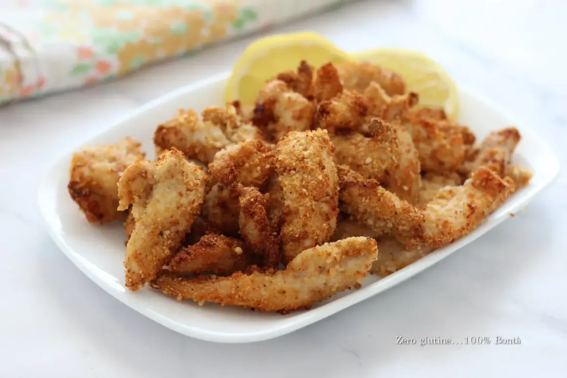 Straccetti di pollo croccanti e dorati, cotti in friggitrice ad aria, serviti con spicchi di limone.