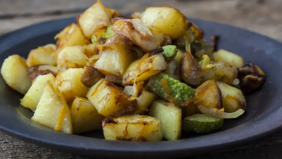 Un piatto invitante di patate e zucchine al forno, dorate e saporite, pronte per essere gustate.