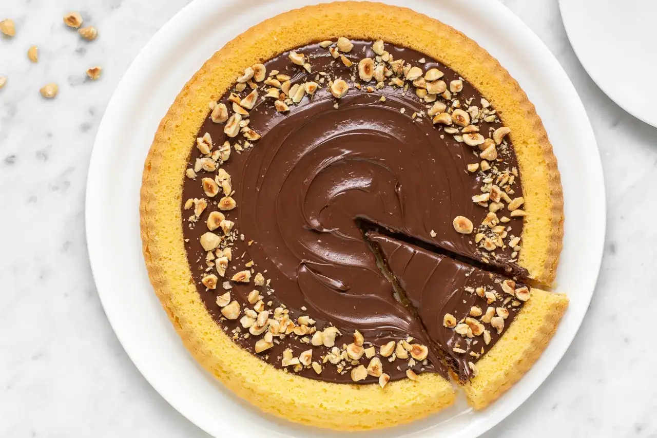 Crostata mascarpone e nutella con nocciole tritate. Una fetta &egrave; stata tagliata, invitando a gustare questa delizia.