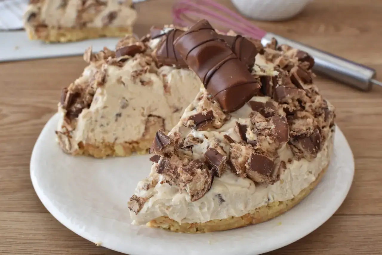 Una golosa torta Kinder Bueno, con crema e pezzi di cioccolato, su un piatto bianco.