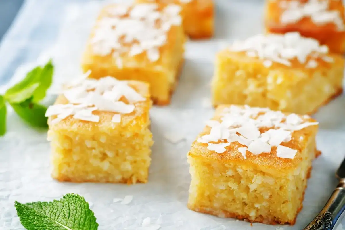 Fette di torta soffice, guarnite con scaglie di cocco e menta fresca. Un delizioso ciambella al cocco da gustare.