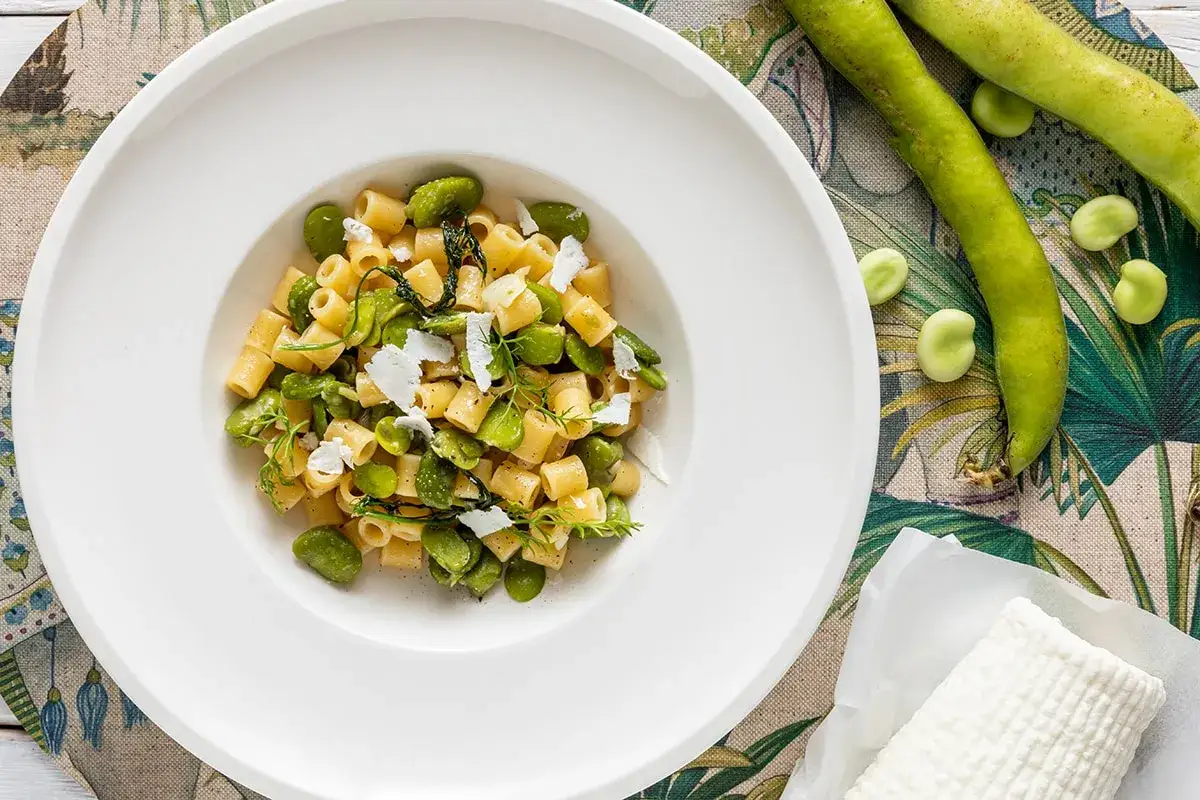 Piatto di pasta con fave fresche, un assaggio della ricetta pasta con le fave fresche alla siciliana, guarnita con ricotta salata.