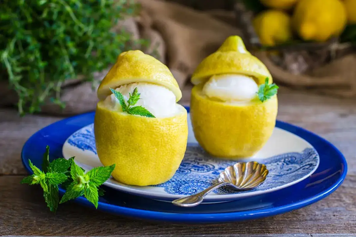 Due limoni scavati, ripieni di fresco gelato al limone e guarniti con menta. Un dessert perfetto fatto in casa con la gelatiera.