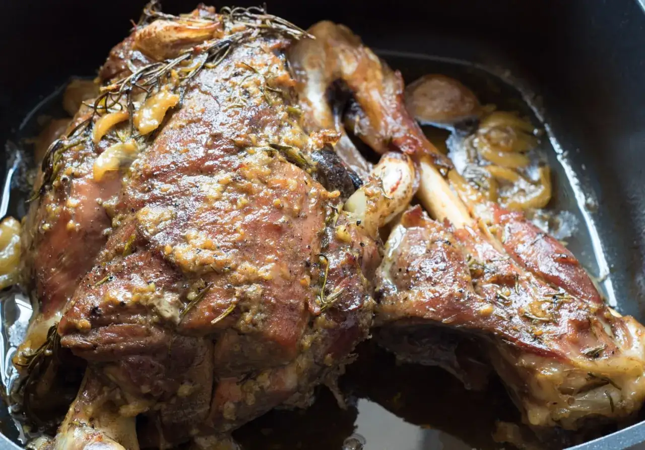 Succulento agnello al forno, dorato e aromatico, con rosmarino e aglio, pronto per essere gustato.