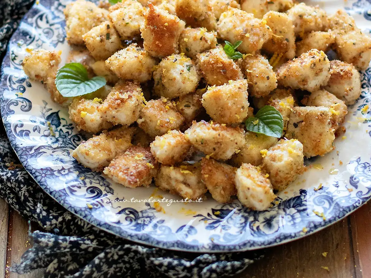 Bocconcini di pollo ricette: croccanti e dorati, guarniti con scorza di limone e menta fresca su un piatto decorato.