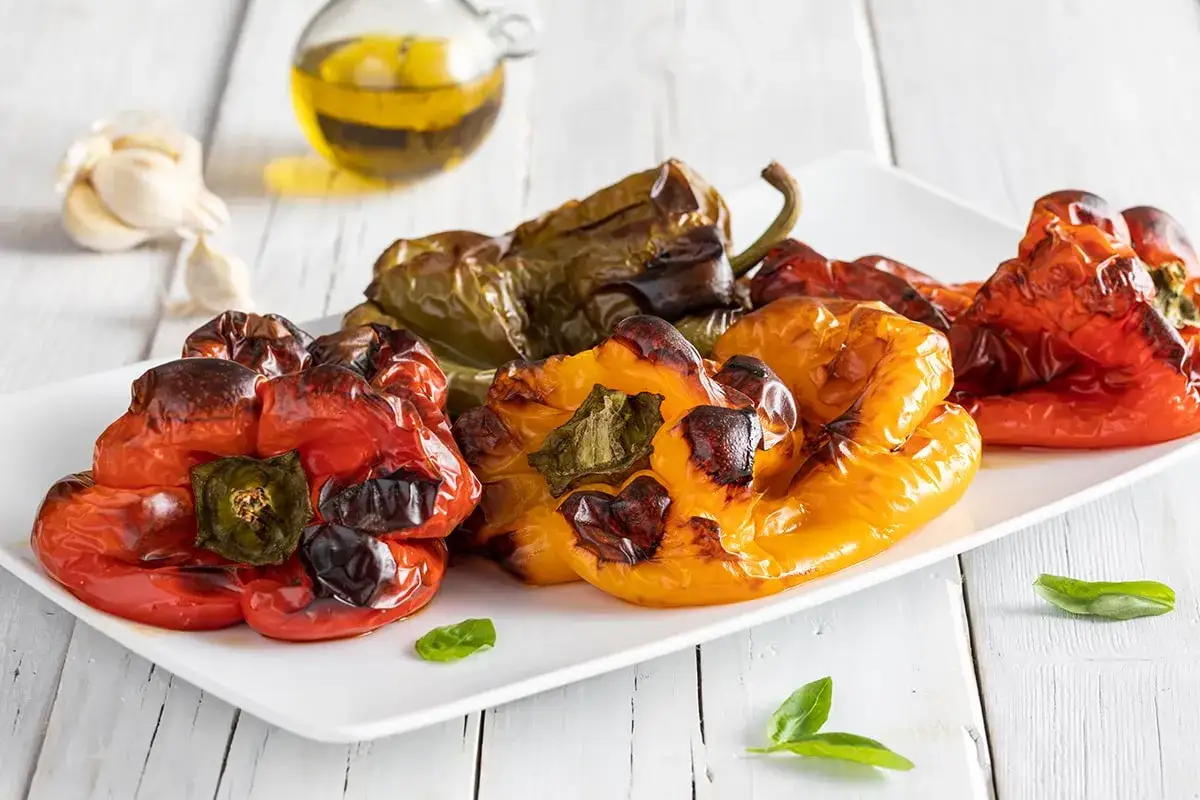 Peperoni arrostiti, pronti per spellare in forno. Un contorno saporito con aglio e olio d'oliva.