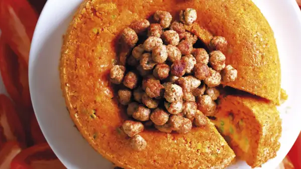 Sartù di riso al forno alla napoletana, un tortino dorato ripieno di piselli e formaggio, coronato da polpettine saporite.