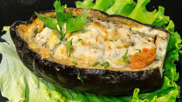 Melanzane ripiene di carne al forno, un piatto gustoso e colorato, servito su un letto di lattuga fresca.
